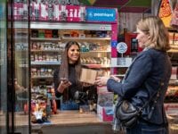 Tiffany Christensen udleverer en pakke til en kunde i butikken Den Søde Tand i Herlev, som er en af de 500 nye udleveringssteder for PostNord. Foto: Henrik Petit